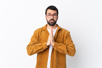 Wall Mural - Caucasian handsome man with beard wearing a corduroy jacket over isolated white background keeps palm together. Person asks for something