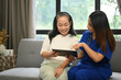 Smiling female healthcare worker showing digital tablet with medical results to senior patient