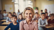 Portrait of smiling female teacher in a class at elementary school looking at camera with learning students on background.