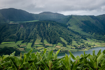 Wall Mural - Blurred leaves at Cumeeiras viewpoint to typical mountains of Caldera das Sete Cidades Lagoon, São Miguel - Azores PORTUGAL