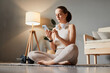 © sementsova321 - Mobile device in exercise. Gym with a smartphone. Sporty slim woman wearing beige tracksuit sitting on floor using online application for home fitness