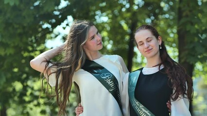 Wall Mural - Russian girls graduate posing with a ribbon and the name - Graduate 2023 on it.