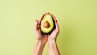 cropped view of woman holding avocado on green background