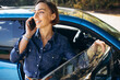 © Petro - Woman talking on the phone and standing by her car