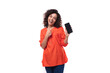 © Ivan Traimak - young caucasian brunette woman with curly hair dressed in orange blouse points smartphone with screen mockup