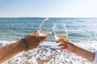© Paopano - Two hands with glasses of wine on the beach. Summer vacations concept.