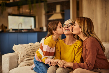 Wall Mural - Three generations. Happy grandmother, her daughter, and grandchild, giving kisses on the cheek.