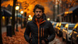© Pavel - Young man in a fashionable jacket stands on an autumnal city street at golden hour, with a serious expression.