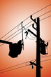 Silhouette of power lineman uses a clamp stick grip all type to install the line cover on energized high-voltage electric power lines. To change the dropout fuse cutout  that is damaged.