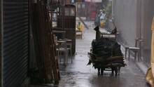 Hard Rain Falls In Heavy Storm On Cart With Stacked Cardboard In Alley