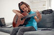 © astrosystem - Kid playing guitar and watching video lessons on a laptop.