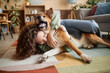 Portrait of young woman playing with happy dog fooling around on floor at home, copy space