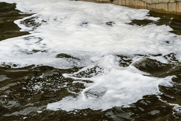 Wall Mural - Foam on the surface of river water in an old sluice.