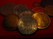 Spanish Gold And Silver Coins, Shields And Reales, On A Red Background