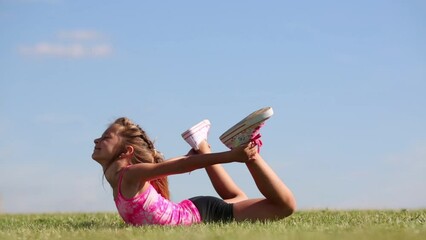 little girl in shorts does exercise basket on green grass