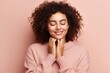 Young beautiful woman with curly hair wearing casual sweater over isolated pink background smiling with hands on chest with closed eyes and grateful gesture on face, Copy space Health concept.