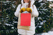 © mdyn - Woman hand with paper eco bag outside in the city park in winter. Women holding two shopping bags outdoors. Concept of holidays and happiness Christmas.