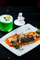 Sticker - White fish with carrot puree, mushrooms in sauce, truffles, microgreens, dinner with green alcoholic cocktail.