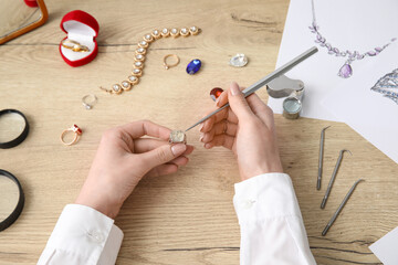 Female jeweler making ring on wooden table, top view