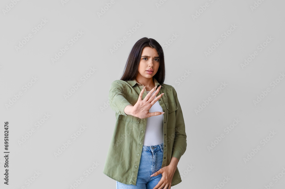 Young woman having panic attack on light background