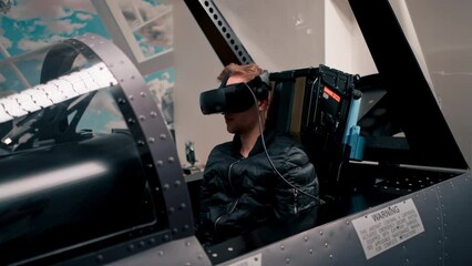 Wall Mural - guy sitting in flight simulator of military plane wearing virtual reality glasses during flight entertainment