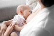 © Pixel-Shot - Young woman breastfeeding her baby at home, closeup