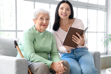 Wall Mural - Senior woman and her daughter with book at home