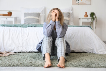 Wall Mural - Depressed young woman sitting in bedroom