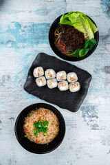 Poster - Rice with chicken, soup with noodle and minced pork and sushi maki rolls with bacon on a blue background.