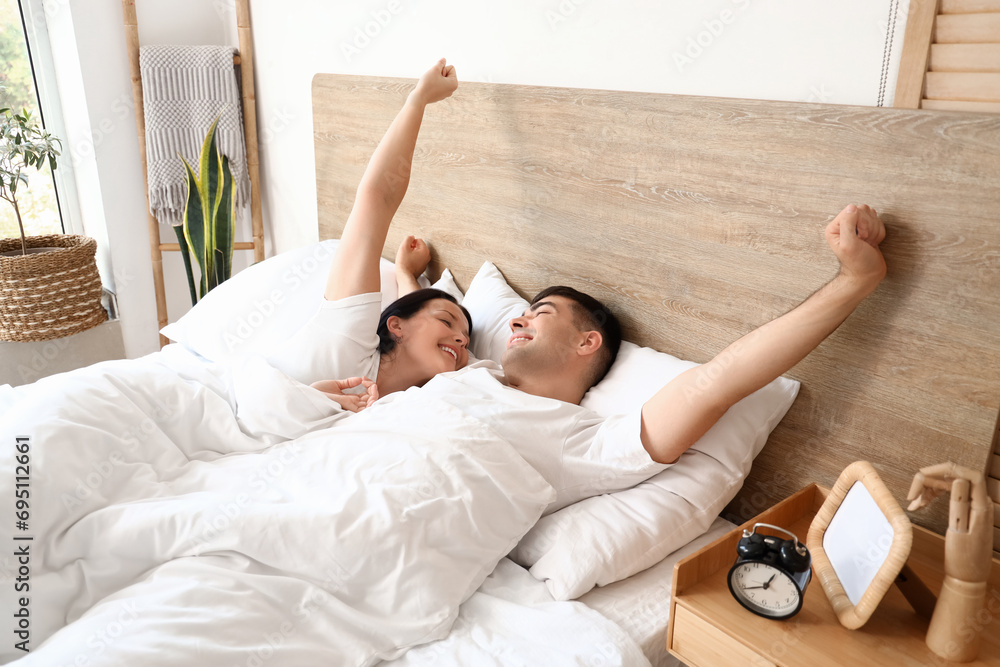 Young couple waking up in bedroom