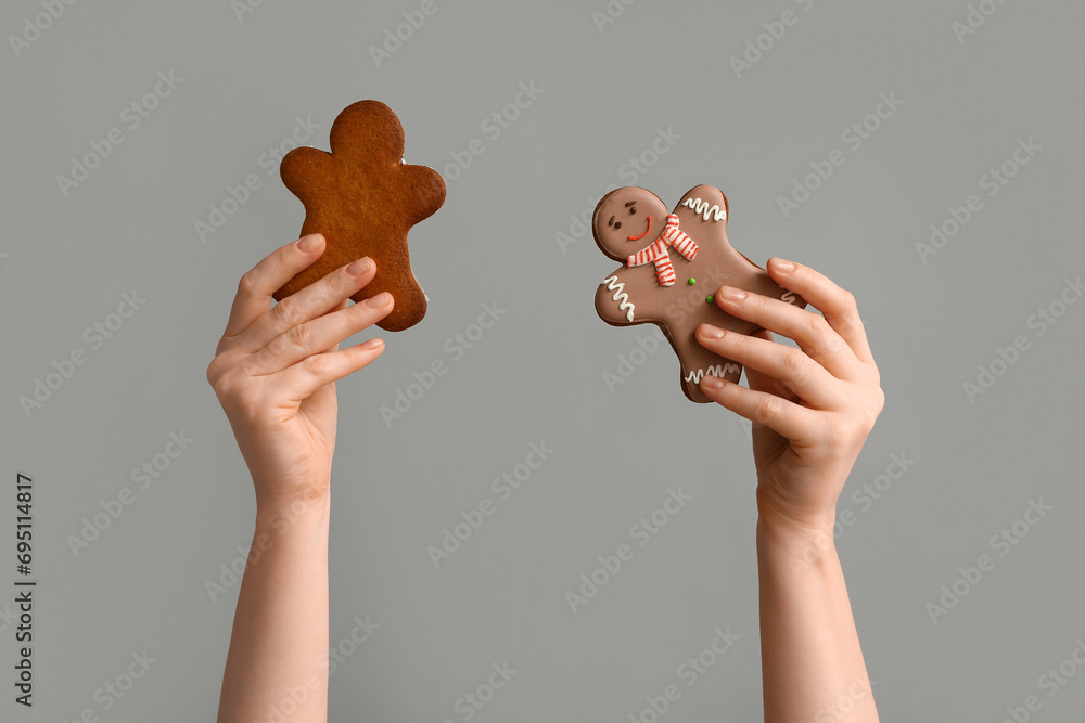 Female hands with Christmas sweet gingerbread cookies on grey background