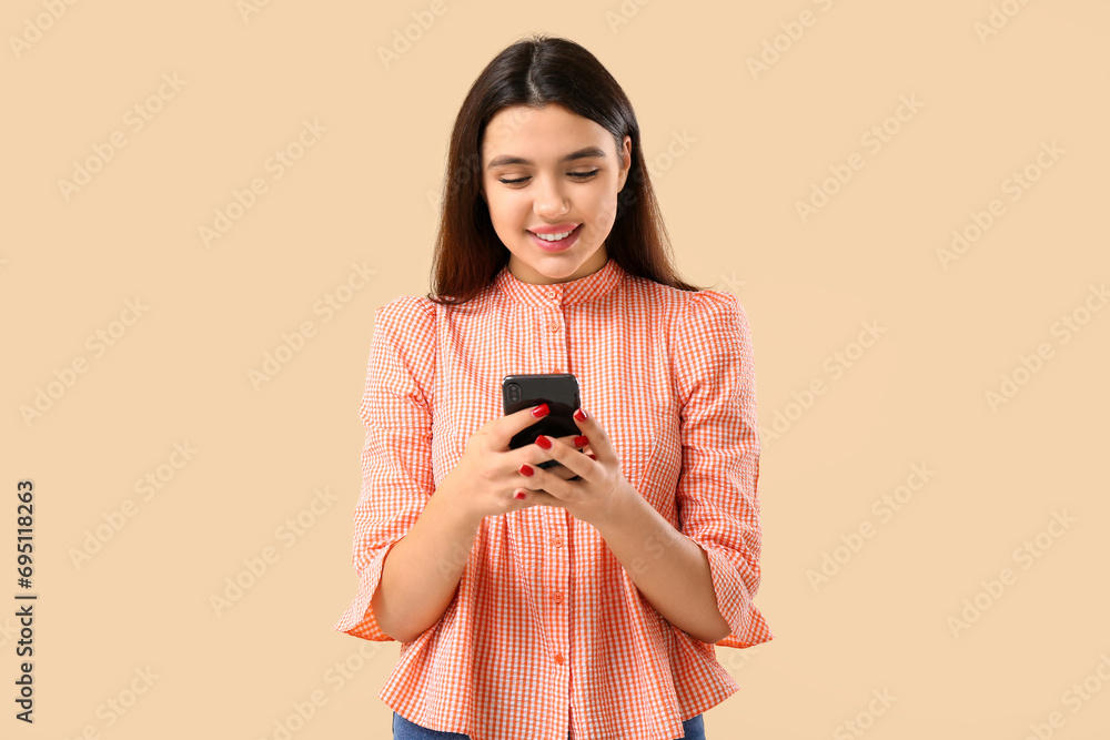 Young woman using mobile phone on beige background. Online dating concept