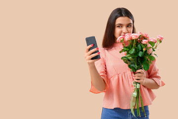 Canvas Print - Young woman with roses and mobile phone on beige background. Online dating concept