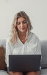 © Daniel - Portrait of one young attractive blonde woman using laptop pc computer on couch relaxing surfing the net at home. Working online concept lifestyle.