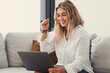 © Daniel - One young happy woman winning and having fun celebrating on couch using laptop pc at home. Euphoric cheerful girl enjoying online prize.