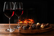 Red wine and chocolate truffles on wooden table against fireplace