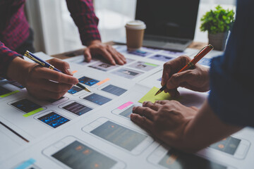 ux developers and ui designers brainstorm on tabletop mobile app layout design planning design color coding at modern office Creative digital development agency.