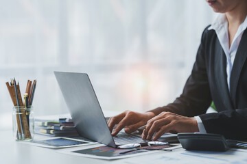 Wall Mural - Asian business woman typing Search for information on your laptop Financial documents, graphs, charts for marketing analysis Tax administration Statistical report on the table in the office.