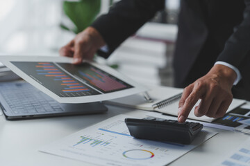 Wall Mural - Asian businesswoman works on laptop and calculates with financial calculator from graphs, statistics, charts. Planning. Business success results in modern office.