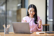 © David - Photo of cheerful joyful young asian business woman in the office working on laptop digital project sitting at desk.