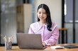 © David - Photo of cheerful joyful young asian business woman in the office working on laptop digital project sitting at desk.