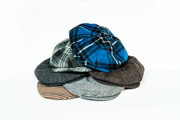 Wall Mural - Stack of classic wool newsboy caps in different colors and patterns on a white background. Classic hats that were popular in the 50s are stacked for photos in the catalogue