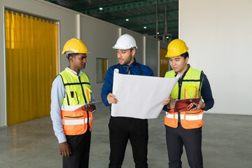 Group of engineers and architects discussing over blueprint and working together in warehouse. Industrial and engineering concept.