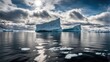 A majestic iceberg formation on the sunny blue shore of the Atlantic Ocean in Greenland. The iceberg is reflected in the calm sea water under a blue sky in daylight.