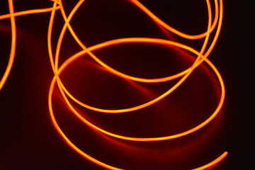 Unusual glowing background of chaotically stacked thin light wires, red glowing tourniquet, illuminated, thin wire placed on a thin background.