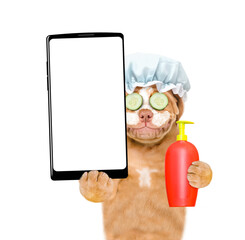 Aufkleber - Mastiff puppy wearing shower cap with pieces of cucumber on it eyes and with cream on it face holds flea shampoo and big smartphone with white blank screen in it paw. isolated on white background