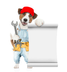 Poster - Funny puppy wearing red cap and denim overalls with tool belt shows empty list and wrench. Isolated on white background