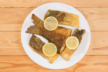 Wall Mural - Fried carp pieces on dish, top view on rustic table