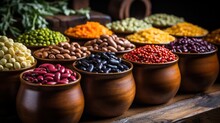 All Kinds Of Different Types Of Beans In Simple Pots On A Wooden Table: Black Beans, Red Beans, White Beans, Fabes, Broad Beans, Alluvian Chickpeas, Green Lentils, Black Lentils.