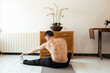 © ADDICTIVE STOCK - Focused young man sitting on mat and stretching leg during workout at home